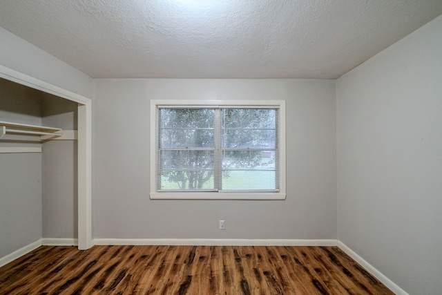 unfurnished bedroom with a closet, dark hardwood / wood-style flooring, and a textured ceiling