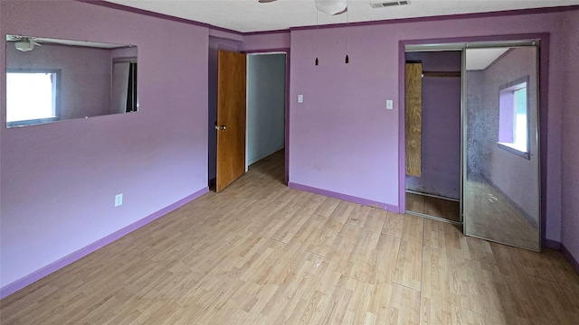 unfurnished bedroom with multiple windows, ceiling fan, a closet, and light wood-type flooring