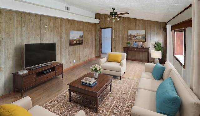 living room featuring ceiling fan, wood walls, wood-type flooring, and lofted ceiling