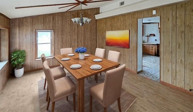 dining area with wooden walls, light hardwood / wood-style flooring, a chandelier, and vaulted ceiling