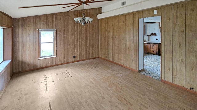 empty room with lofted ceiling, light wood-type flooring, and wooden walls