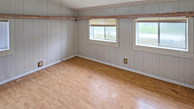 spare room featuring wooden walls, light hardwood / wood-style flooring, and vaulted ceiling