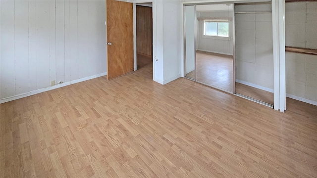 unfurnished bedroom featuring wood walls and light wood-type flooring