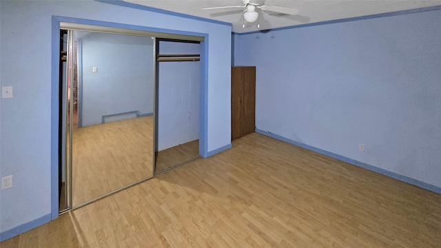 unfurnished bedroom featuring ceiling fan, light wood-type flooring, ornamental molding, and a closet