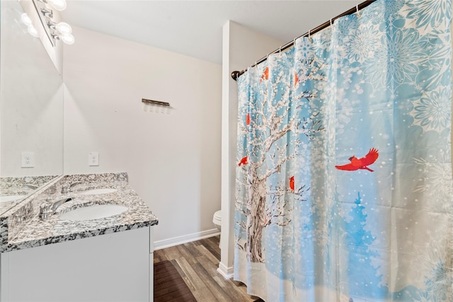 bathroom with hardwood / wood-style floors, vanity, toilet, and walk in shower