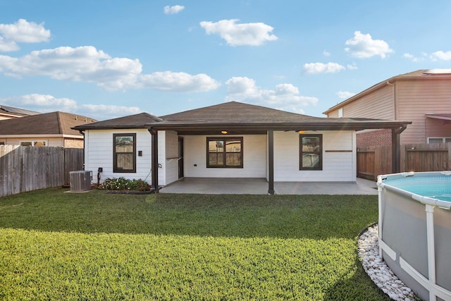 rear view of house featuring a fenced in pool, a lawn, a patio, and central AC unit