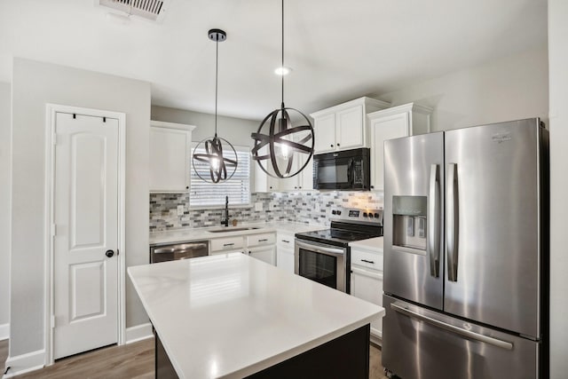 kitchen with white cabinets, sink, a center island, and stainless steel appliances