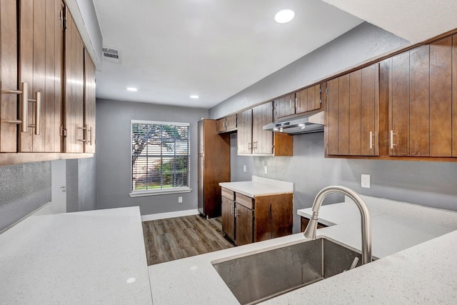 kitchen with light stone countertops, sink, and wood-type flooring