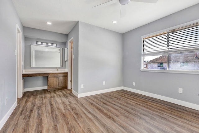 unfurnished bedroom with hardwood / wood-style floors, ceiling fan, and built in desk