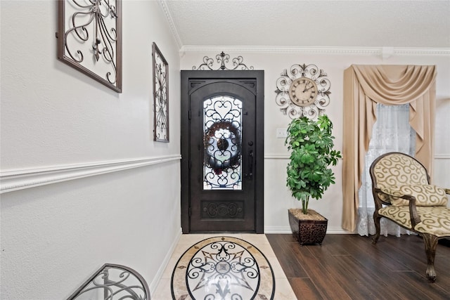 entrance foyer with hardwood / wood-style flooring, a textured ceiling, and ornamental molding