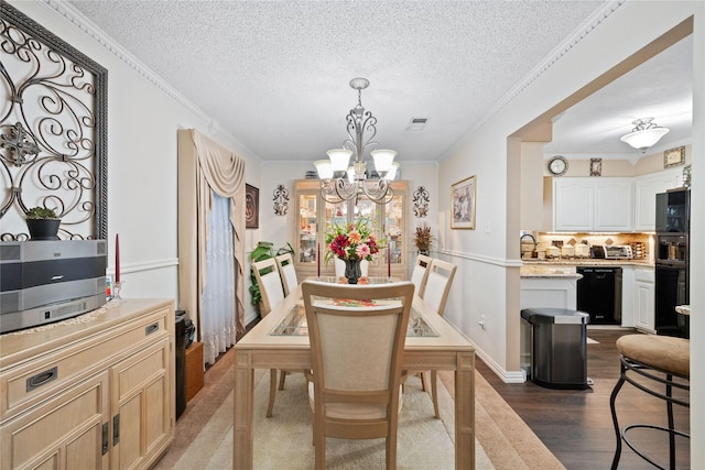 dining space featuring a textured ceiling, dark wood-type flooring, an inviting chandelier, and crown molding