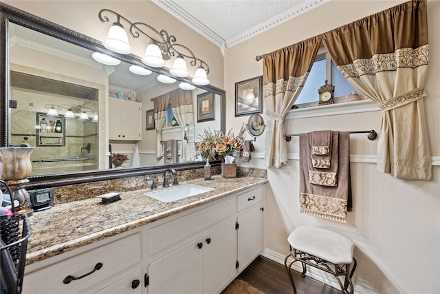 bathroom featuring a textured ceiling, crown molding, and vanity