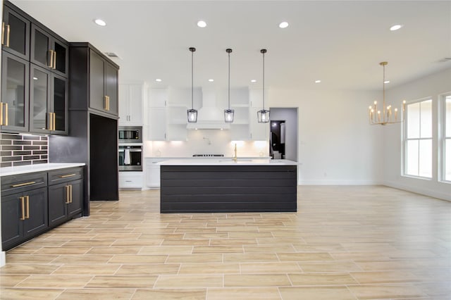 kitchen with backsplash, pendant lighting, light wood-type flooring, and custom exhaust hood