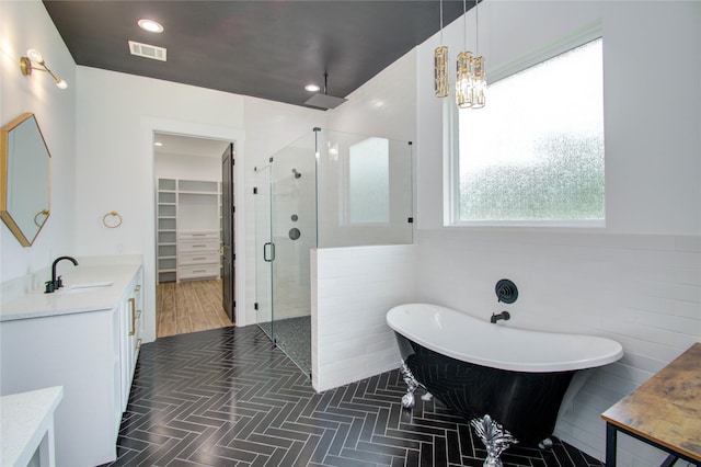 bathroom with a notable chandelier, vanity, separate shower and tub, and tile walls