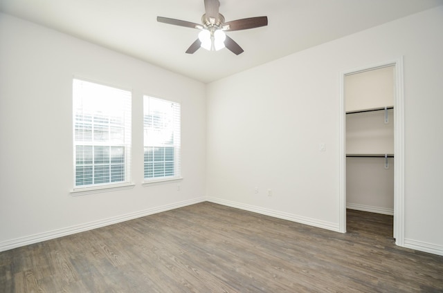 unfurnished bedroom with ceiling fan, dark hardwood / wood-style floors, a walk in closet, and a closet