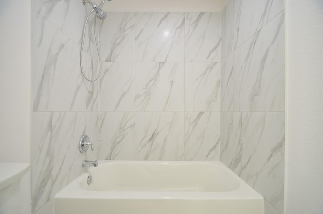 bathroom with tiled shower / bath combo and toilet