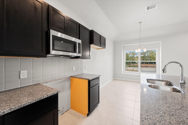 kitchen featuring backsplash, sink, stone counters, a chandelier, and hanging light fixtures