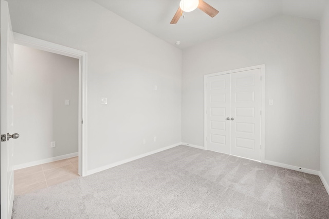 unfurnished bedroom featuring ceiling fan, a closet, light carpet, and vaulted ceiling