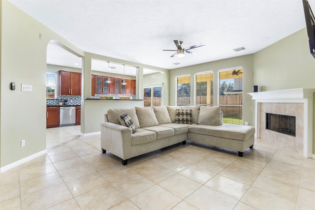 tiled living room featuring ceiling fan and a fireplace