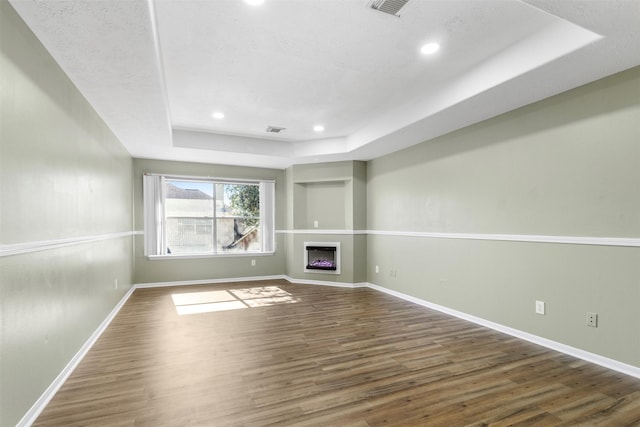 unfurnished living room with a tray ceiling and dark wood-type flooring