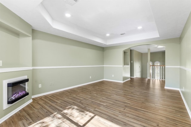 unfurnished living room with a tray ceiling and wood-type flooring