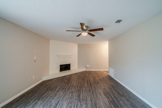 unfurnished living room featuring dark hardwood / wood-style floors, a large fireplace, a textured ceiling, and ceiling fan