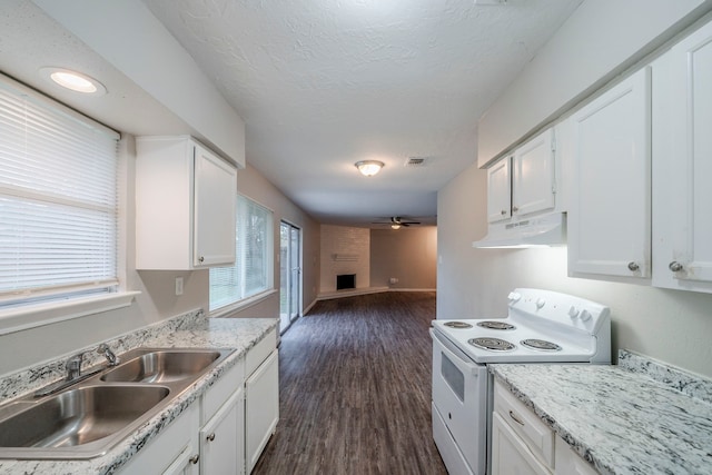 kitchen featuring white range with electric stovetop, a large fireplace, white cabinetry, and sink