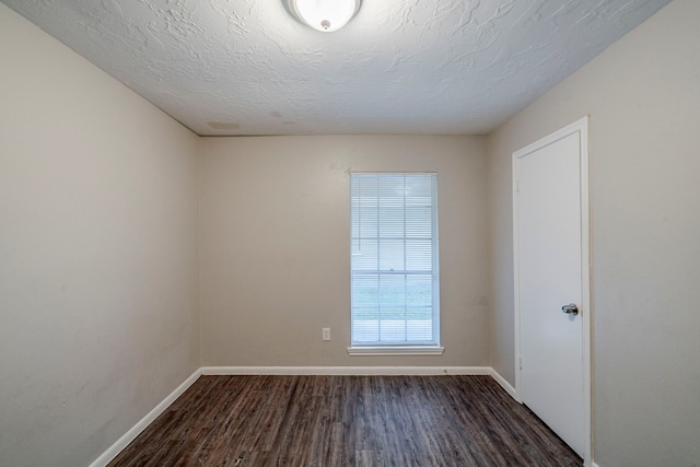 empty room with a textured ceiling and dark hardwood / wood-style floors