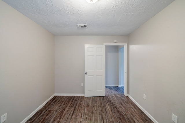 empty room featuring dark hardwood / wood-style flooring and a textured ceiling