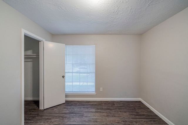 unfurnished bedroom with dark hardwood / wood-style floors, a textured ceiling, and a closet