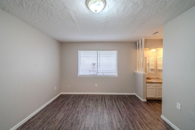 spare room with a textured ceiling, dark hardwood / wood-style floors, and sink