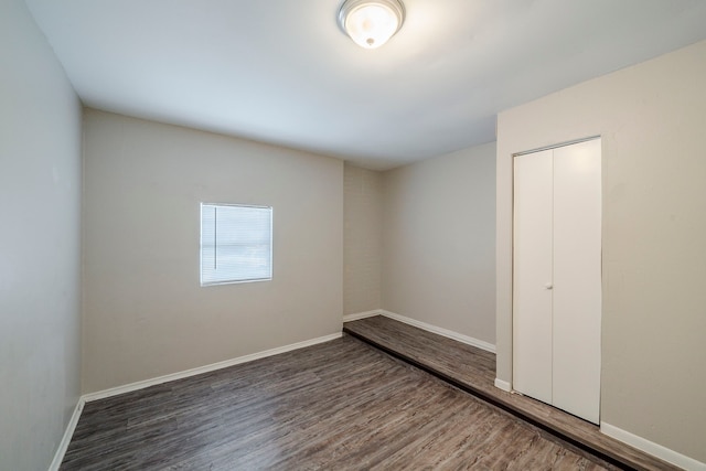 unfurnished bedroom with dark hardwood / wood-style flooring and a closet