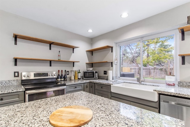 kitchen with sink, light stone counters, gray cabinetry, and stainless steel appliances