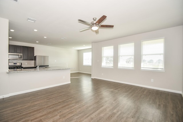 unfurnished living room with ceiling fan, sink, and dark wood-type flooring