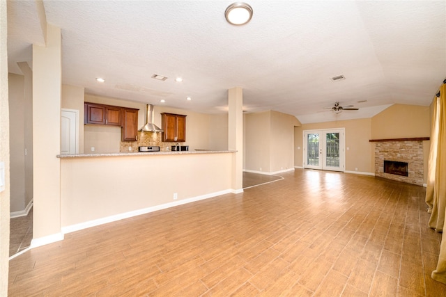 unfurnished living room featuring ceiling fan, french doors, light hardwood / wood-style floors, lofted ceiling, and a textured ceiling