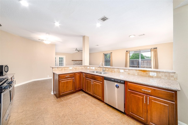 kitchen with kitchen peninsula, light stone countertops, backsplash, stainless steel appliances, and sink