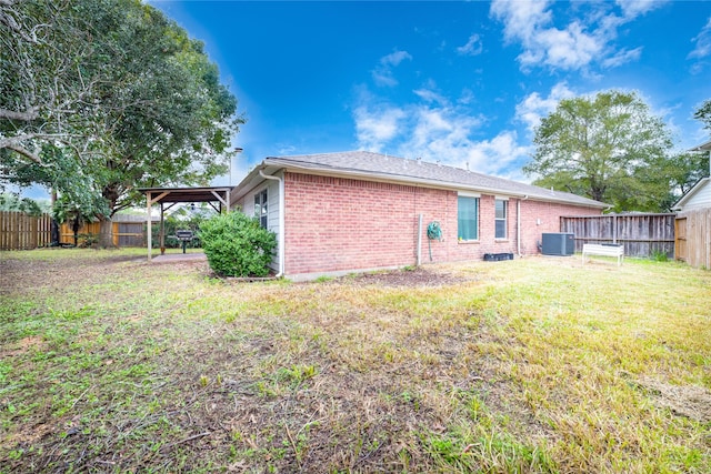 back of house with central AC unit and a lawn