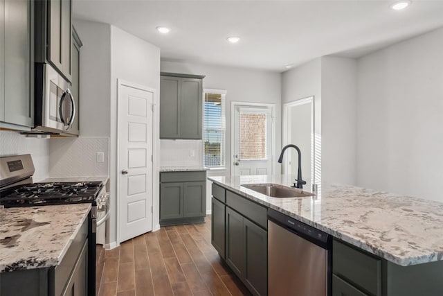 kitchen with sink, stainless steel appliances, dark hardwood / wood-style flooring, decorative backsplash, and a center island with sink