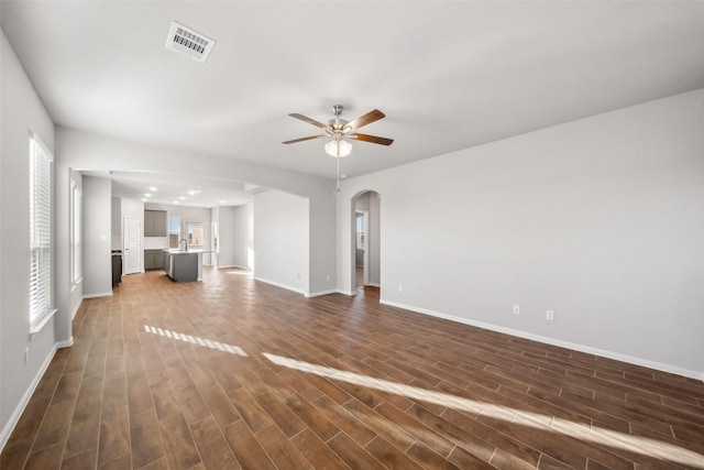 unfurnished living room featuring sink, dark hardwood / wood-style floors, plenty of natural light, and ceiling fan