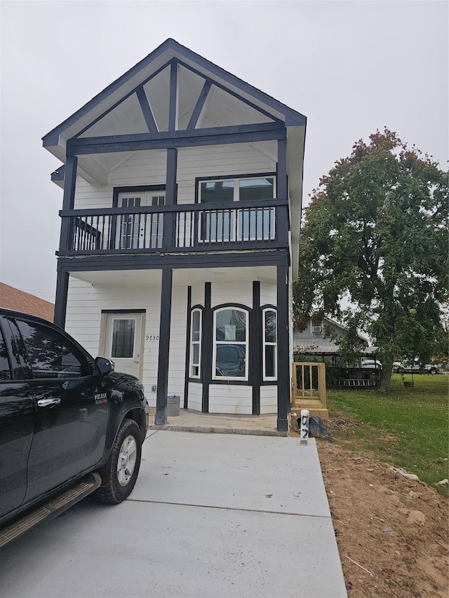 view of front of home with a balcony and a front lawn