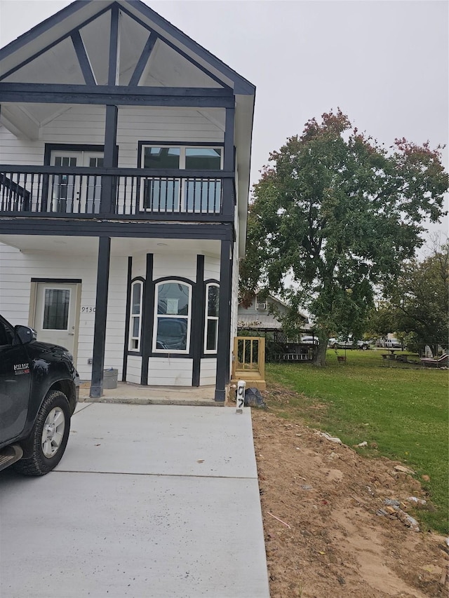 view of front of home with a balcony and a front lawn