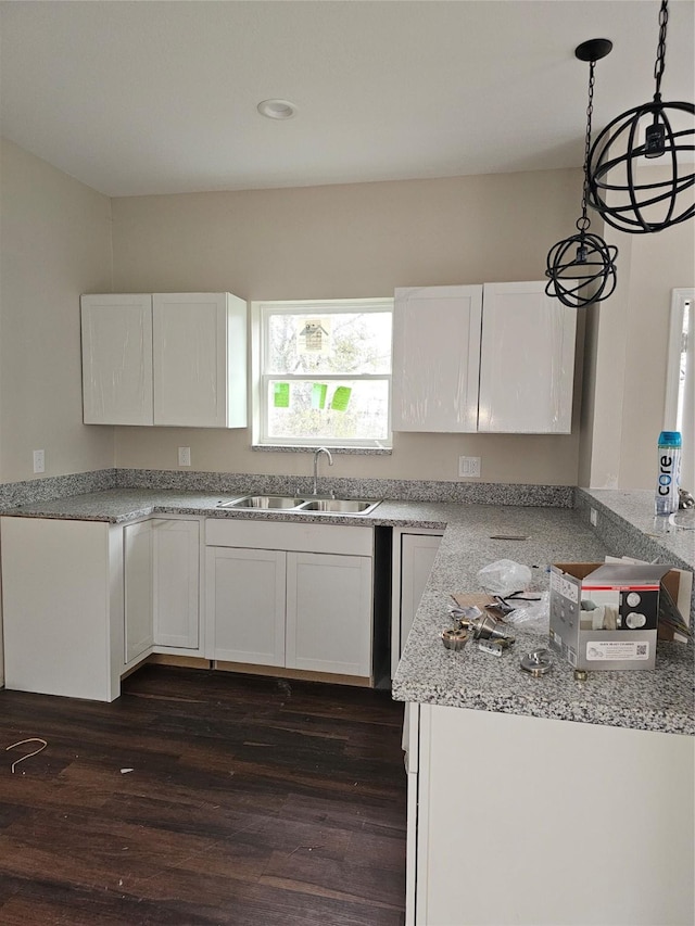 kitchen with white cabinetry, sink, dark wood-type flooring, light stone counters, and decorative light fixtures