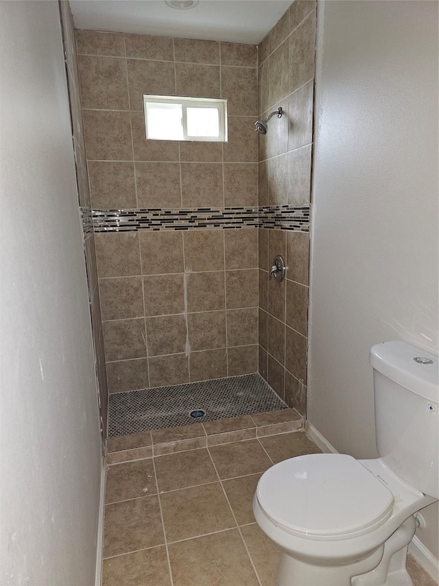 bathroom featuring tile patterned floors, toilet, and a tile shower