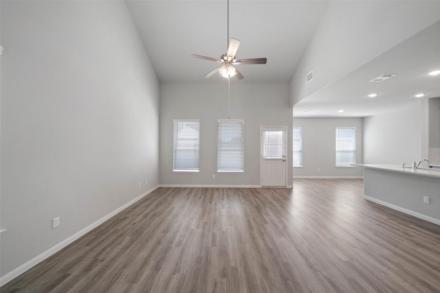 unfurnished living room with ceiling fan, dark hardwood / wood-style flooring, high vaulted ceiling, and sink