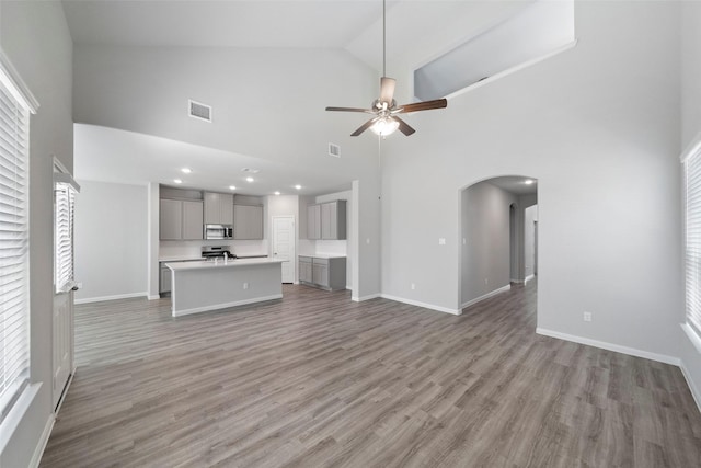 unfurnished living room with ceiling fan, hardwood / wood-style floors, and high vaulted ceiling