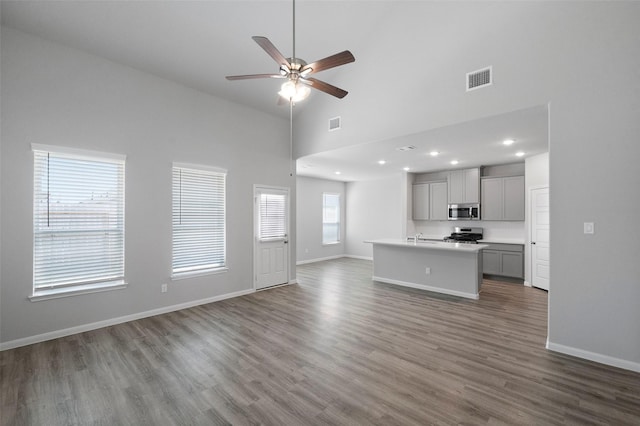 unfurnished living room with hardwood / wood-style floors, high vaulted ceiling, and ceiling fan