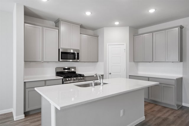 kitchen featuring gray cabinetry, sink, dark hardwood / wood-style floors, a kitchen island with sink, and appliances with stainless steel finishes