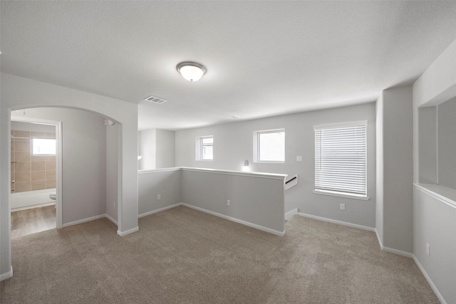 unfurnished room with light colored carpet and a textured ceiling