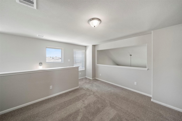 empty room with carpet flooring and a textured ceiling