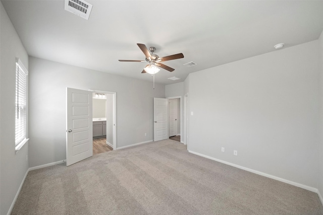 unfurnished bedroom featuring ceiling fan, light colored carpet, and ensuite bathroom